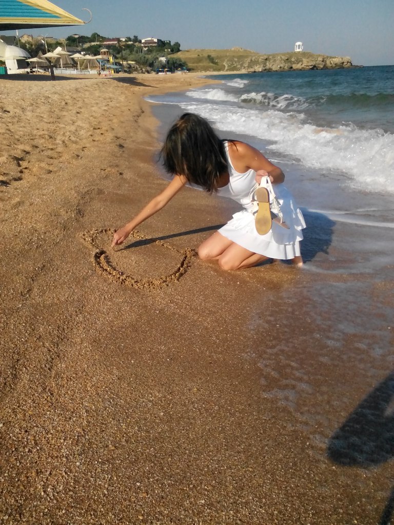 девушка чертит сердце на песке